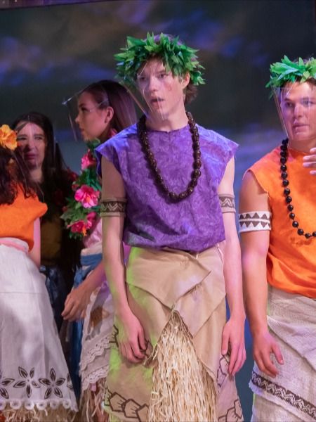 a group of people standing next to each other on a stage with flowers in their hair