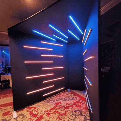 the room is decorated in black and blue with neon lights on the wall behind it