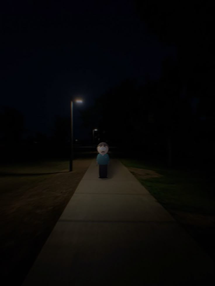 a person standing on a sidewalk in the dark at night with their head turned to the side