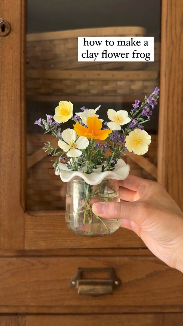 a person holding a jar with flowers in it