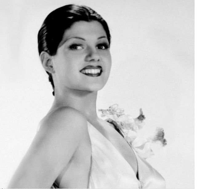 a black and white photo of a woman in a dress with flowers on her shoulder