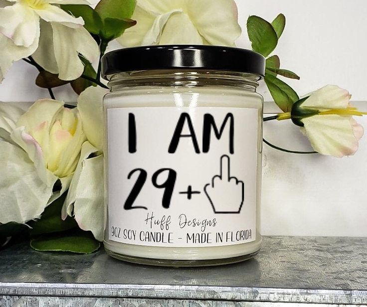 a candle with the words i am 29 + plus on it next to some flowers