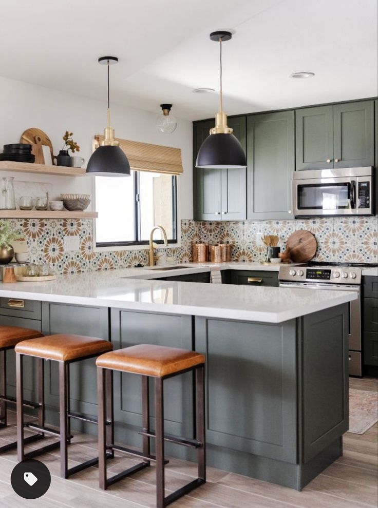 a kitchen with green cabinets and wooden stools in front of the countertop area