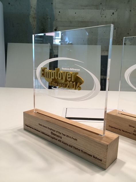 two trophies sitting on top of a white table next to each other with gold lettering