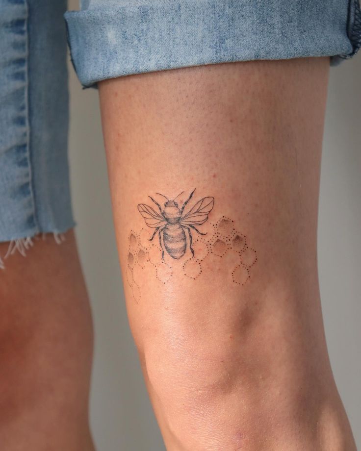 a woman's leg with a tattoo on it and a bee sitting next to her