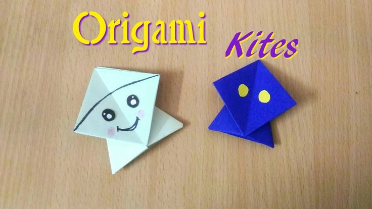 two origami kites sitting on top of a wooden table