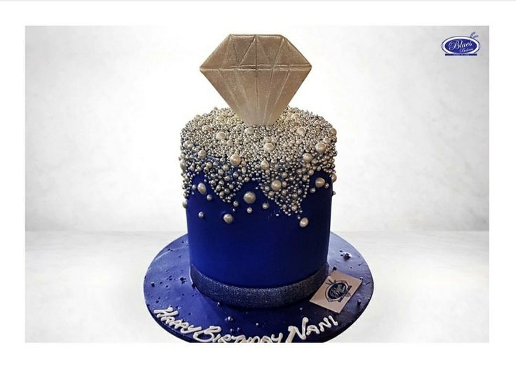 a blue cake with silver decorations on it's top and the bottom is covered in pearls