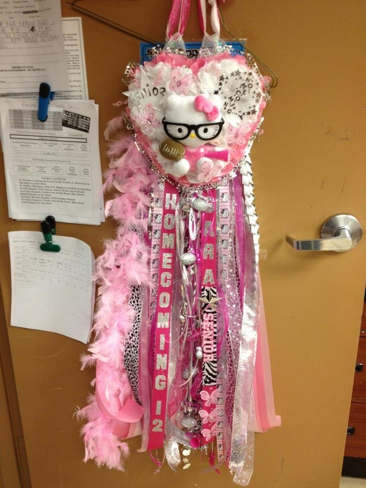 a door hanger decorated with pink and white hair, glasses and ribbons hanging from it's side