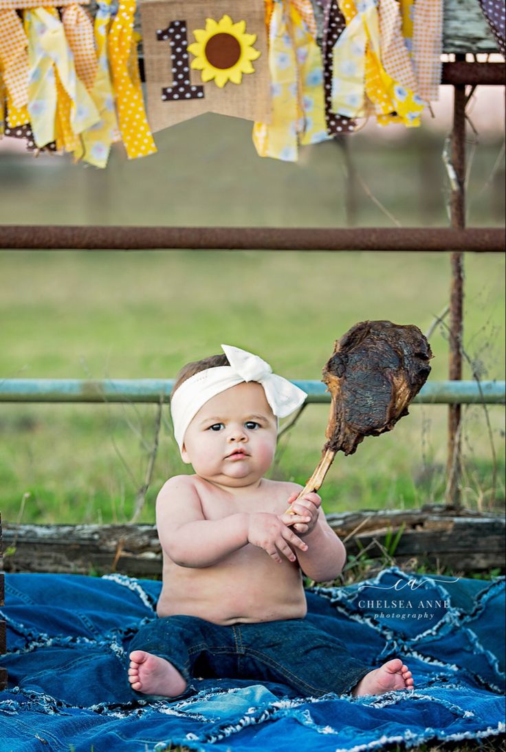 a baby sitting on a blanket holding a bird