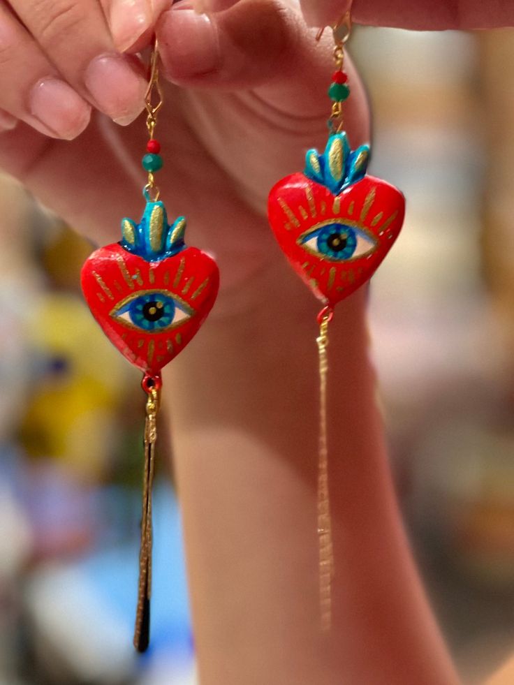 Heart shaped pendant earrings handmade by Edith Orozco, from Leon, Guanajuato, Mexico! Edith paints each heart amulet by hand, then carefully sets them in gold plated fixtures. Every piece is unique. Heart Amulet, Mexican Gifts, Heart Shaped Pendant, Happy Hippie, Pendant Earring, Heart Shape Pendant, Scarf Jewelry, Handmade Clothes, Pendant Earrings