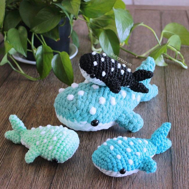 three crocheted stuffed animals sitting on top of a wooden table next to a potted plant