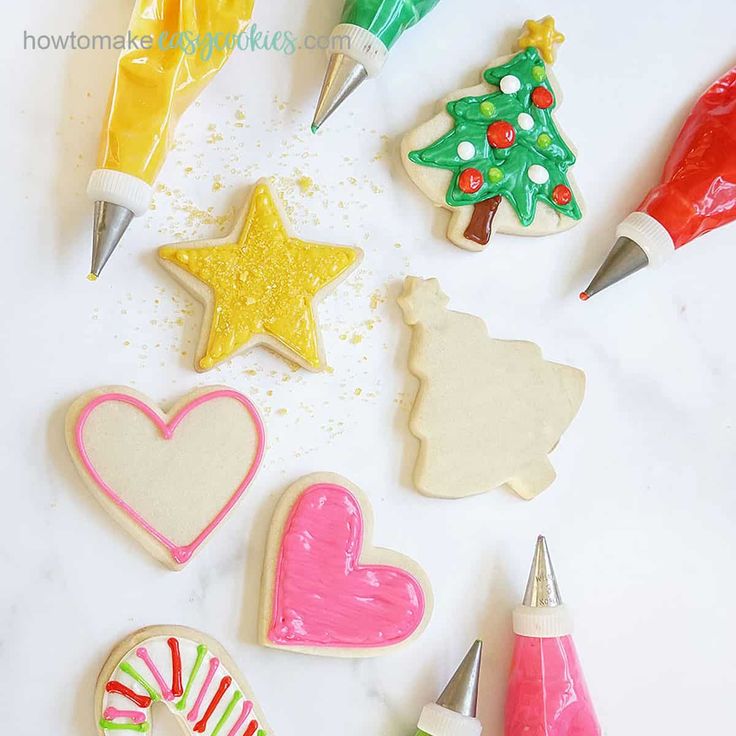 decorated christmas cookies and cookie cutters on a white counter top with candy canes