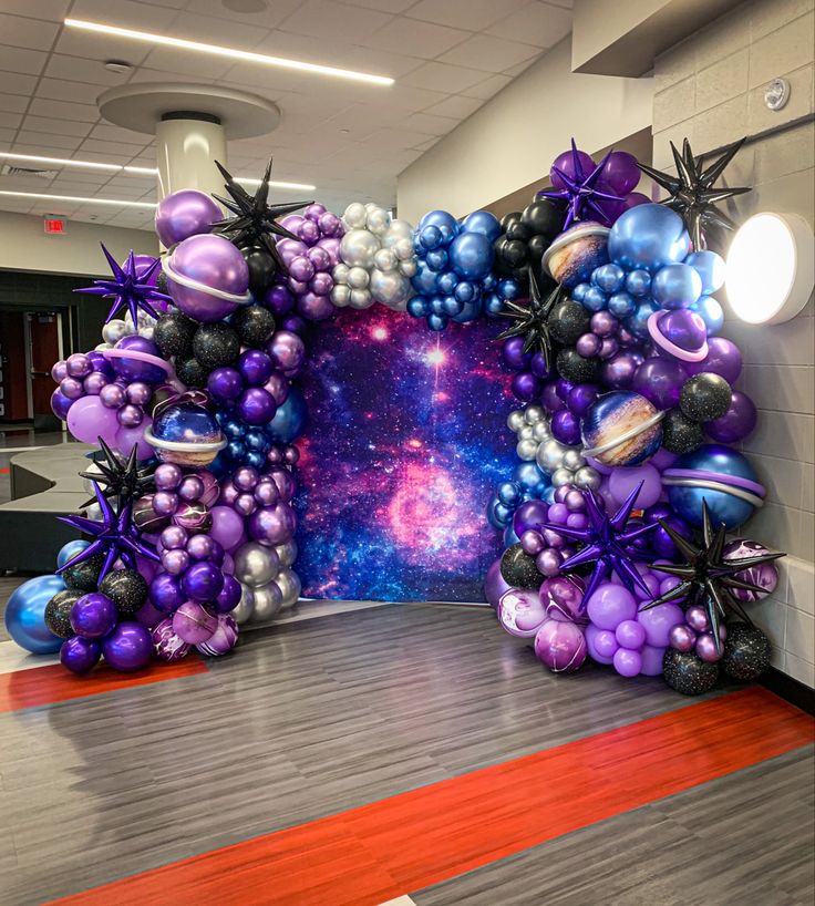 an arch made out of balloons in the shape of planets and stars is displayed on a wooden floor