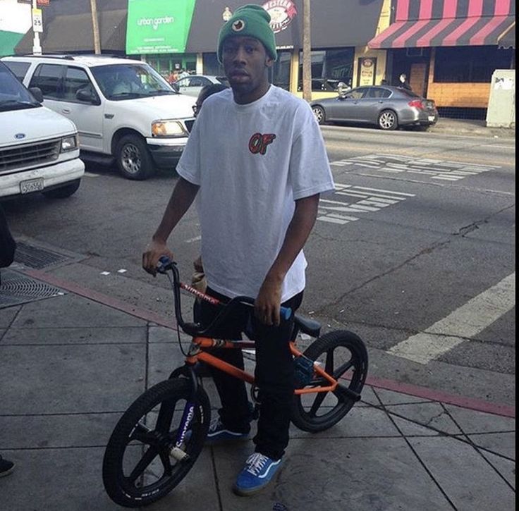 a man standing next to his bike on the sidewalk