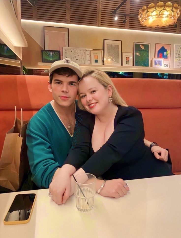 a man and woman sitting at a table in a restaurant with their arms around each other