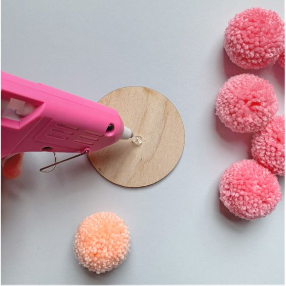 a person is making pom - poms out of yarn and glue on a white surface