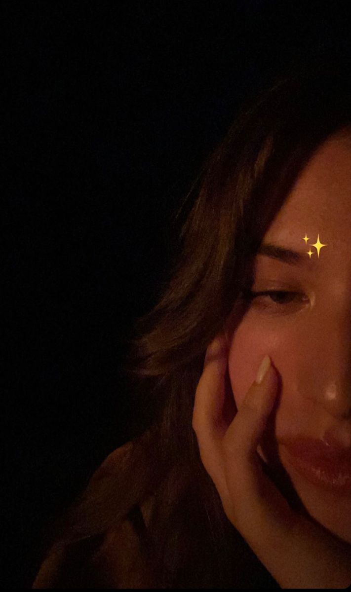 a woman holding her hand to her face while looking at the stars on her forehead