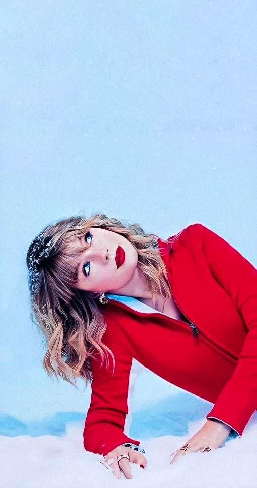 a woman in red is leaning on the snow with her hands behind her head and eyes closed