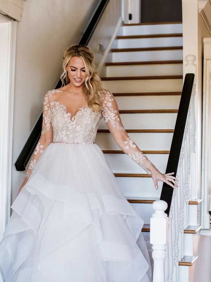 a woman in a wedding dress standing on the stairs