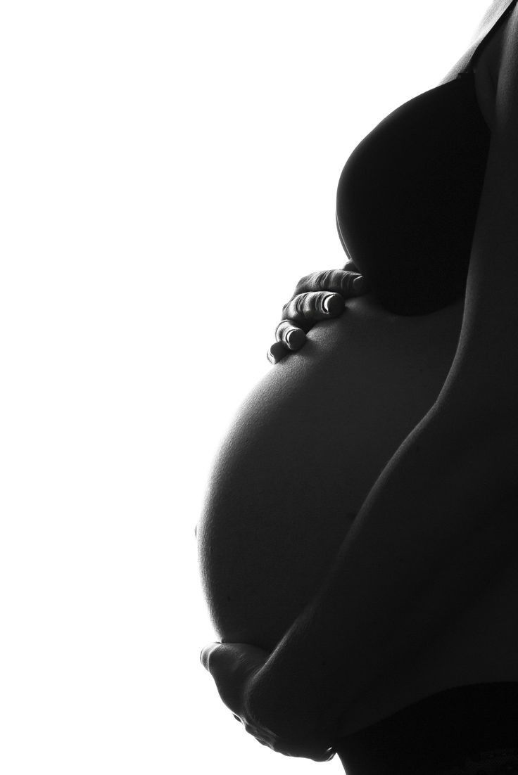 a pregnant woman's belly is shown in black and white, with her hands on her hips