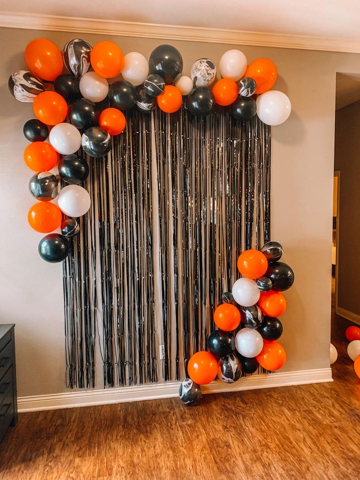 an orange and black balloon arch in the middle of a room