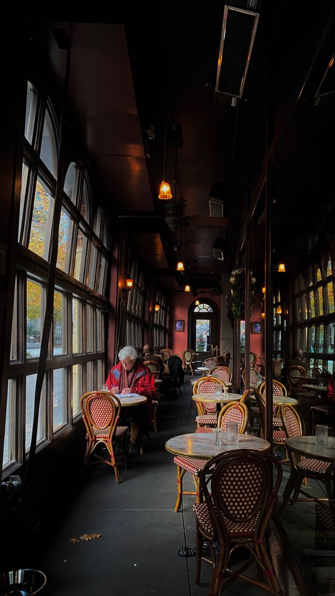 people sitting at tables in a restaurant with large windows on either side of the room