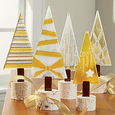 four christmas trees made out of wood and ribbons on a table with white walls in the background