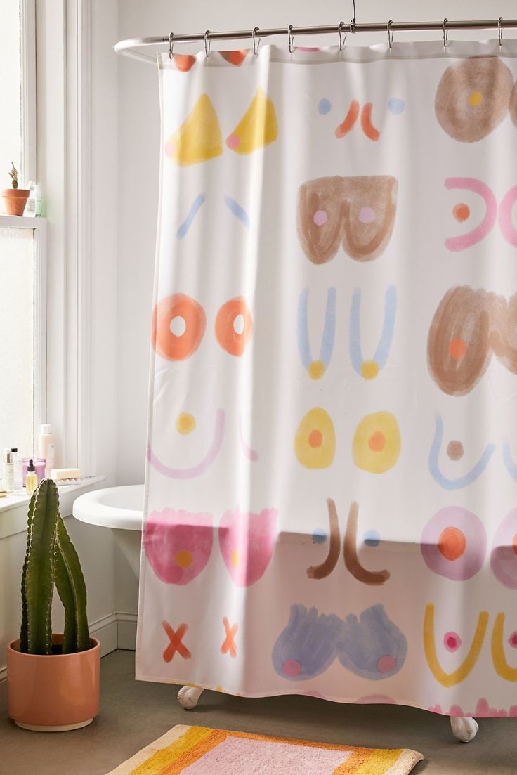 a bathroom with a shower curtain, rug and potted cactus on the floor in front of it