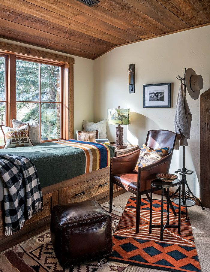 a bed room with a neatly made bed next to a chair and a desk in front of a window