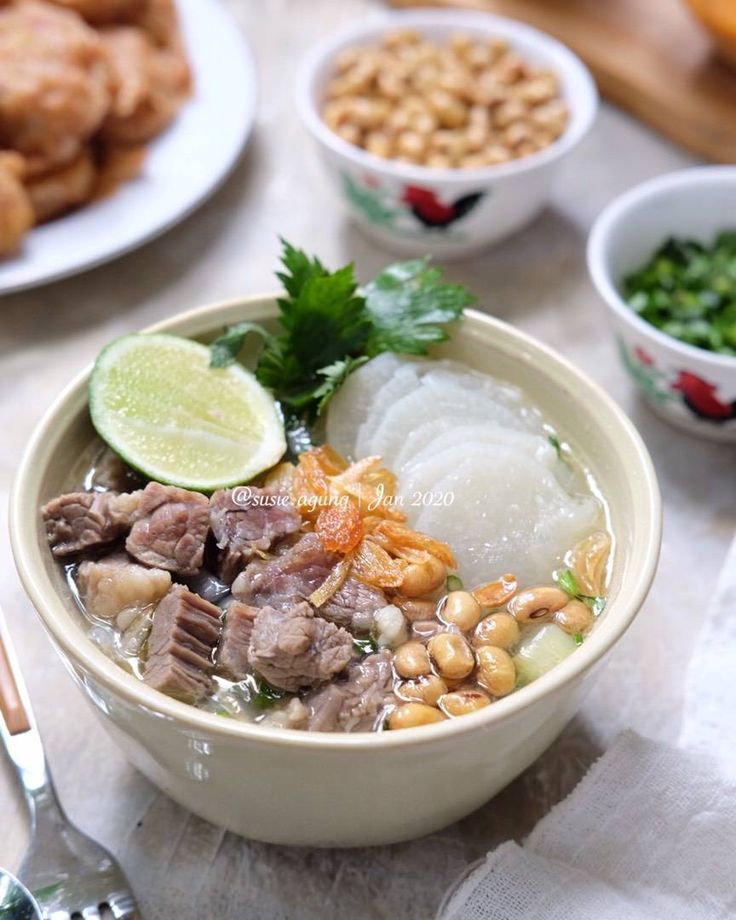 a bowl filled with meat and vegetables on top of a table next to other dishes