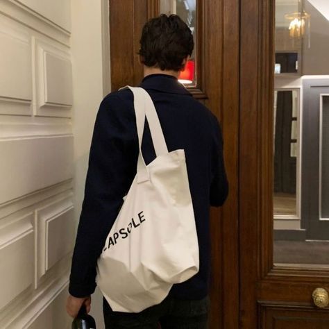 a person standing in front of a door with a white bag on their back,