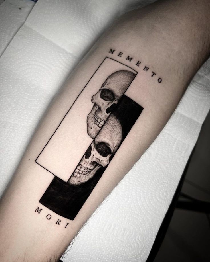 a man's arm with a tattoo on it that has two skulls in the middle