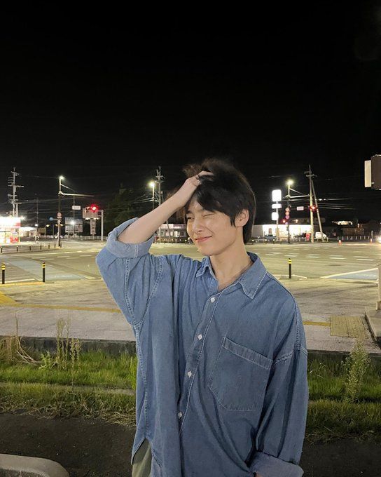 a man standing in front of a street at night with his hand on his head