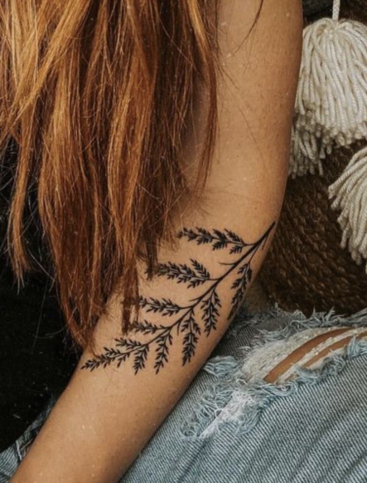 a woman's arm with a tattoo on it that has leaves growing out of it