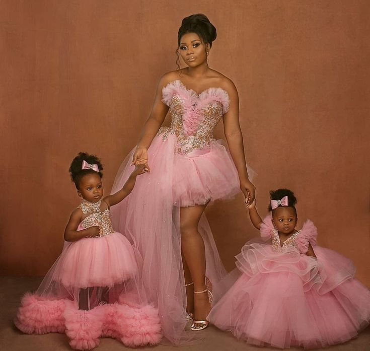 a woman and two children in pink dresses