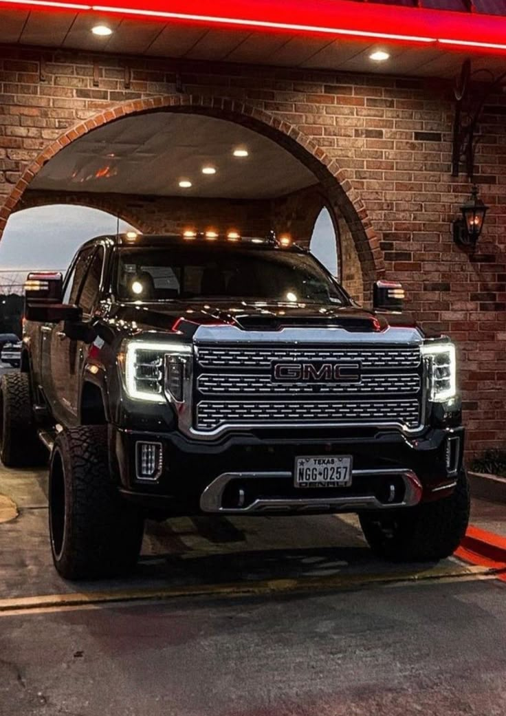 a black truck parked in front of a brick building with a red light above it