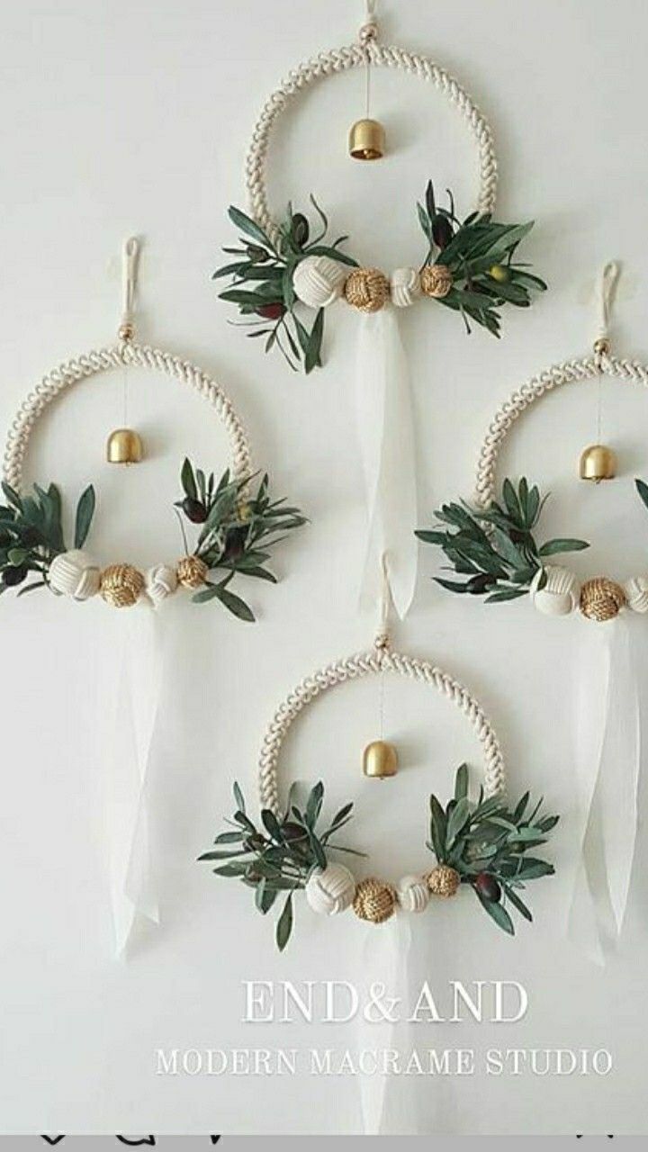 three white wreaths hanging on the wall with gold balls and greenery in them