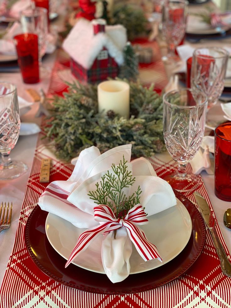 a table set for christmas dinner with red and white place settings