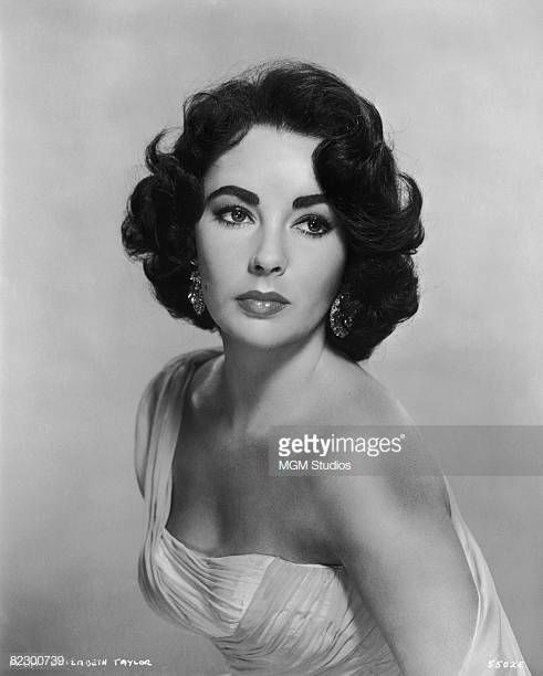 an old black and white photo of a woman wearing a strapless dress with large earrings