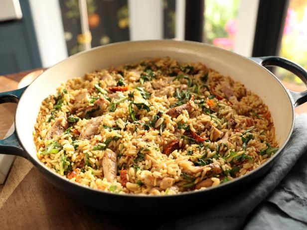 a pan filled with rice and vegetables on top of a wooden table