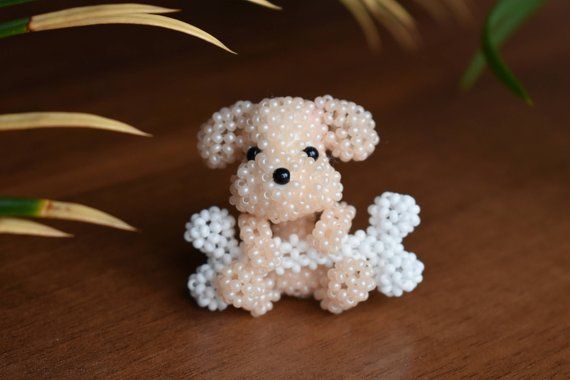 a small beaded dog sitting on top of a wooden table next to some plants