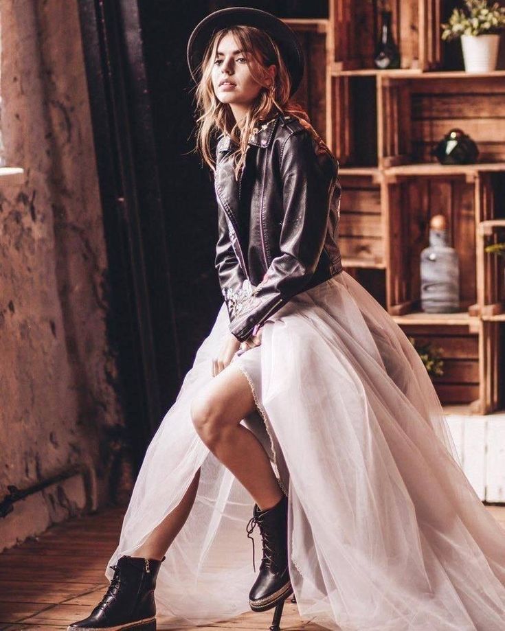 a woman sitting on top of a wooden floor wearing a white dress and black boots