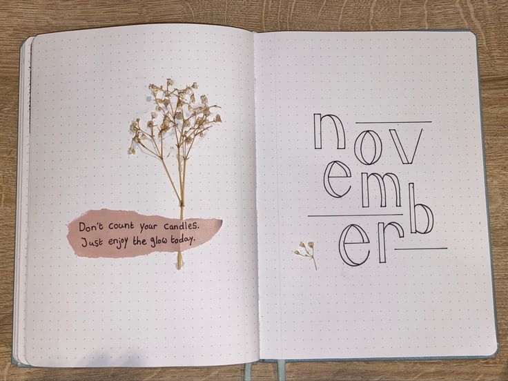 an open notebook with the words november written on it and a plant in its middle