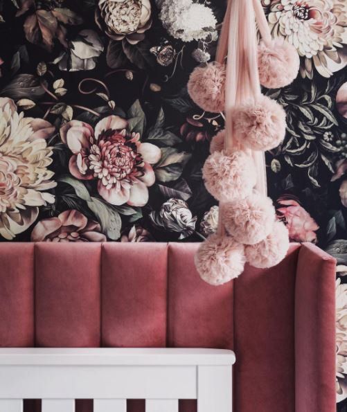 a baby's crib with flowers and pom poms hanging from it