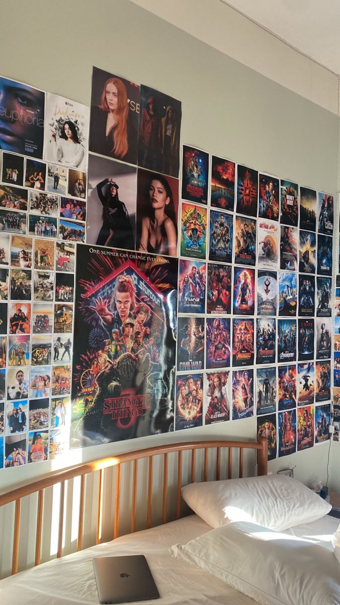 a bedroom with posters on the wall and a laptop computer sitting on the bed in front of it