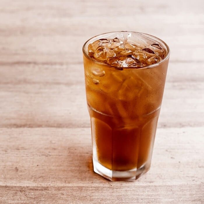 an iced drink in a tall glass on a wooden table