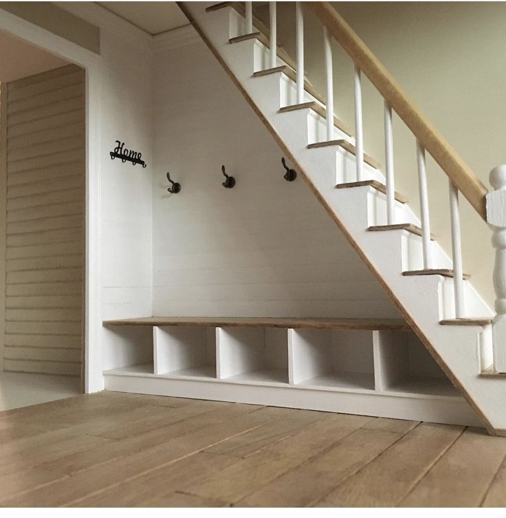 an empty room with some shelves under the stairs and two birds on the wall next to it