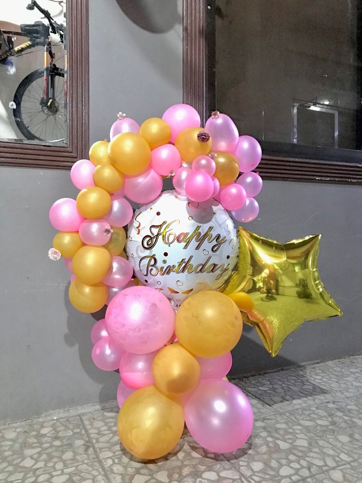 a birthday balloon arch with balloons and heliums on the ground in front of a mirror