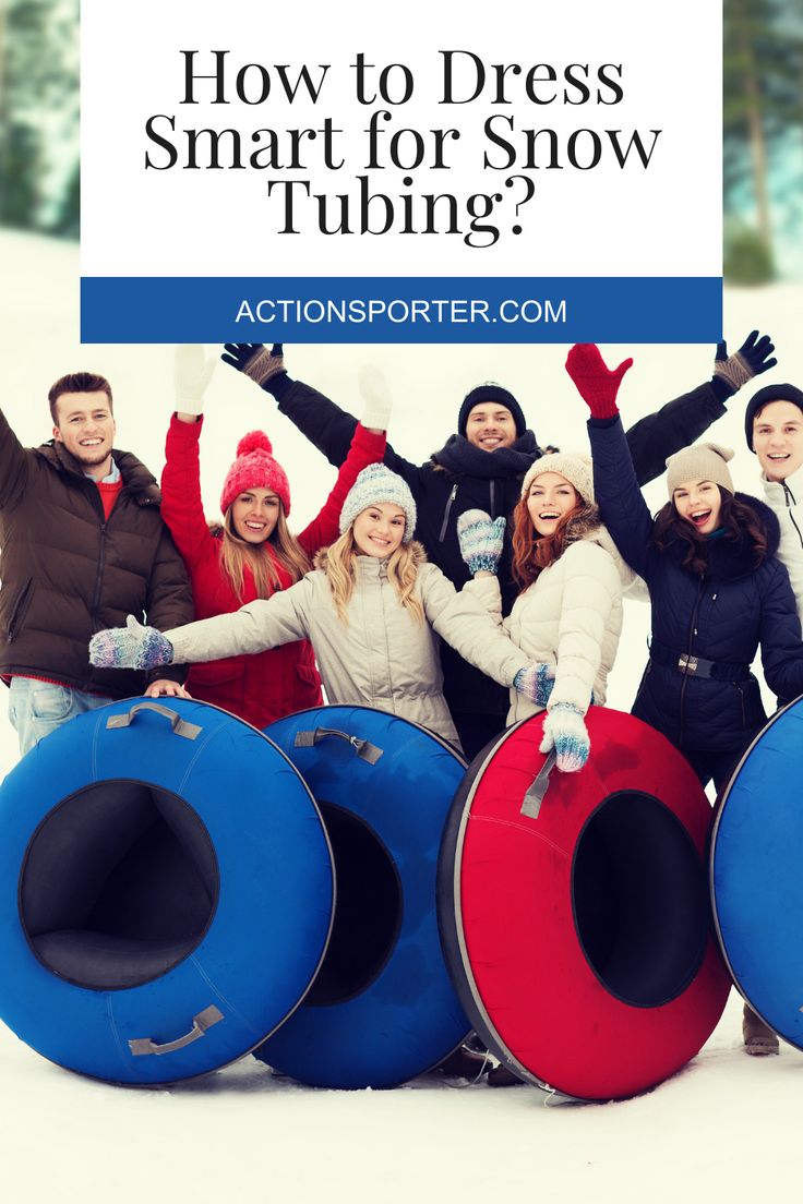 a group of people standing in the snow with their arms up and two large tubes behind them