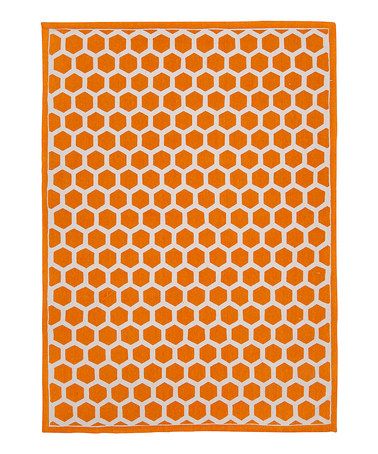 an orange and white rug with hexagonal shapes on the bottom, in front of a